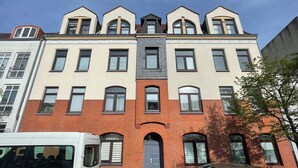 A multi-story building with a mix of brick and plaster facades, large windows, and a central entrance with an archway. - Cozy vacation apartment - perfect for a short break all inclusive for 5 people (Bremerhaven)