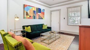 Una sala de estar con un sofá verde, una mesa de centro y un cuadro en la pared.
