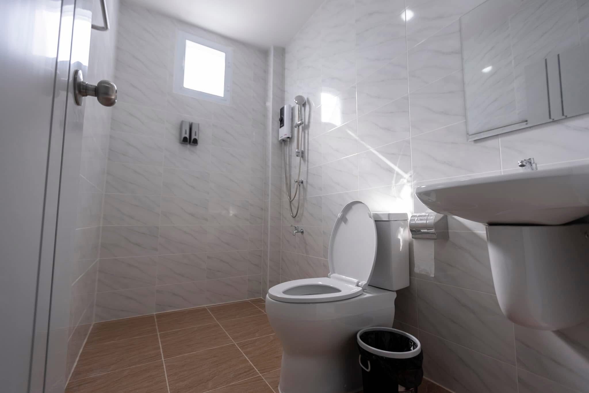 A modern bathroom with a toilet, shower, and sink.