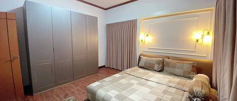 Un dormitorio con un armario amplio, una cama con edredón a cuadros y dos lámparas de pared.