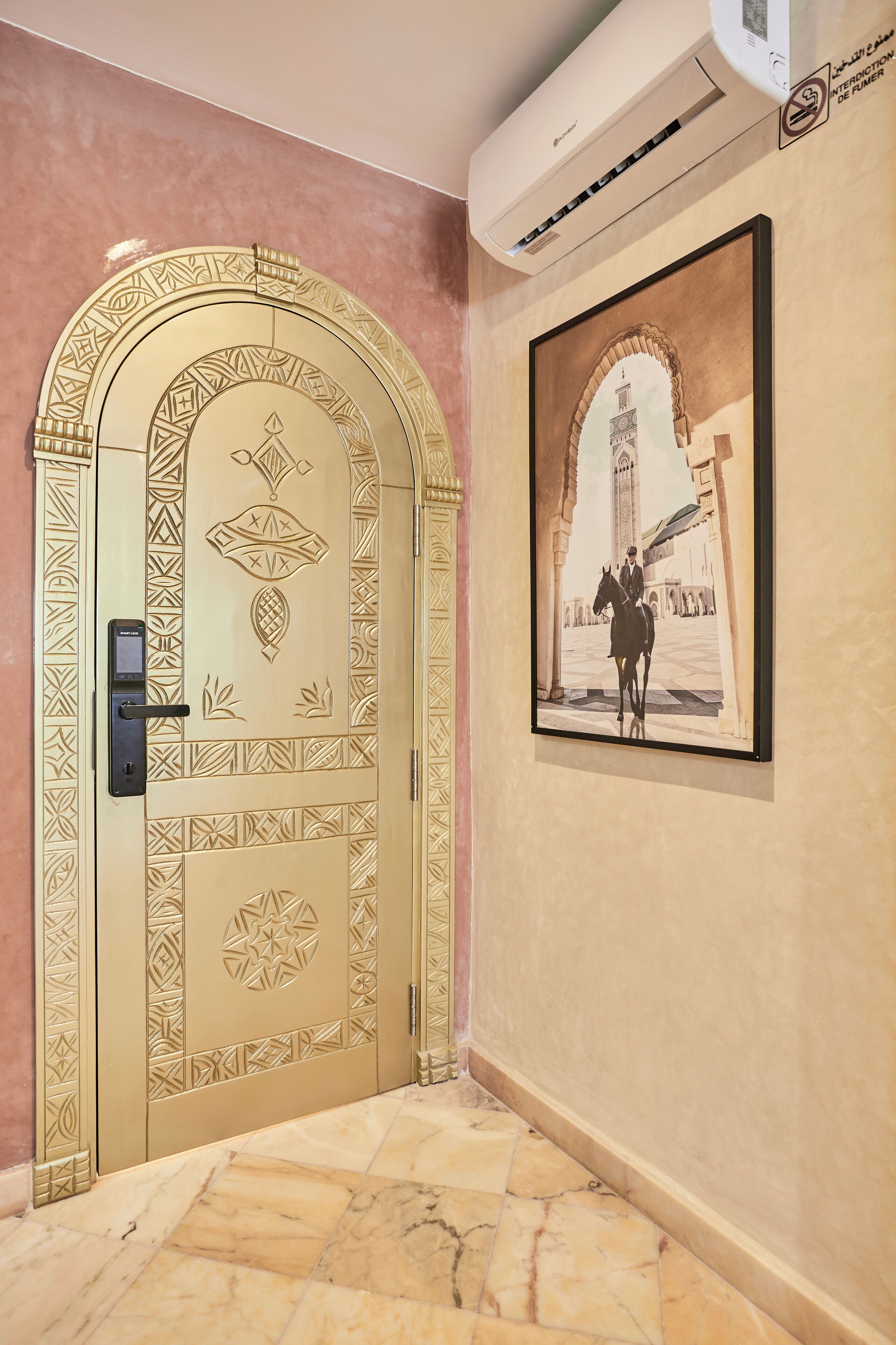 A hallway with a decorative door, a framed photograph on the wall, and an air conditioning unit.
