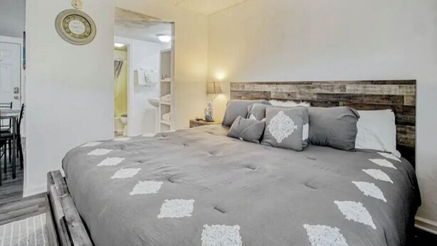 A bedroom with a large bed, a wooden headboard, and a nightstand with a lamp.