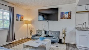 A modern living room with a grey sofa, a coffee table, and a flat-screen TV mounted on the wall.