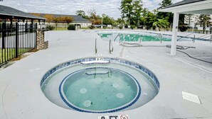 A swimming pool with a 3 FT depth marker, surrounded by a concrete deck and a covered seating area.