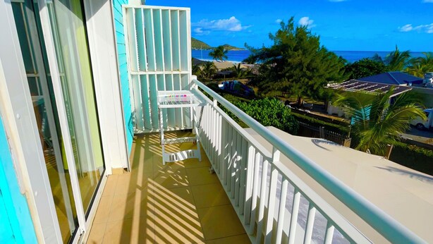 A balcony with a view of the ocean and palm trees. - Beautiful apartment with sea view (Marigot)
