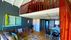 A spacious living area with a high ceiling, a balcony with red railings, a dining area with a table and chairs, and a kitchen in the background. - Beautiful apartment with sea view (Marigot)