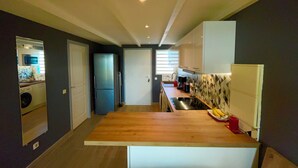 A modern kitchen with a wooden countertop, a built-in oven, and a refrigerator. - Beautiful apartment with sea view (Marigot)