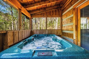 A wooden cabin with a hot tub and large windows overlooking a forest. - Quiet-Hot Tub-Fireplace-Honeymoon-Hiking-Relax (Sevierville)