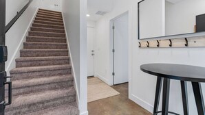 A staircase leading to a door, a round bar stool, and a wall-mounted mirror. - Summer Getaway: Hot tub & Cold Plunge, Gear-dryer (Salt Lake City)