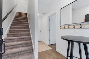 A staircase leading to a door, a round bar stool, and a wall-mounted mirror. - Summer Getaway: Hot tub & Cold Plunge, Gear-dryer (Salt Lake City)