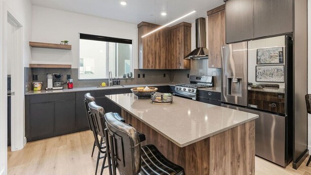 A modern kitchen with a central island, dark cabinetry, stainless steel appliances, and a large window. - Summer Getaway: Hot tub & Cold Plunge, Gear-dryer (Salt Lake City)