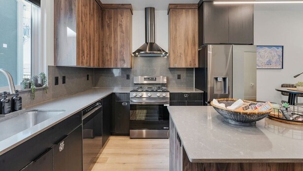 A modern kitchen with wooden cabinets, stainless steel appliances, and a large island with a basket of bread. - Summer Getaway: Hot tub & Cold Plunge, Gear-dryer (Salt Lake City)