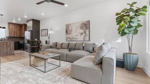 A modern living room with a sectional sofa, a coffee table, and a potted plant. - Summer Getaway: Hot tub & Cold Plunge, Gear-dryer (Salt Lake City)