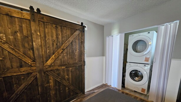 Una sala de bugaderia amb una porta de fusta gran i dues rentadores amuntegades.