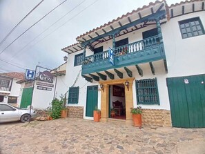 Un immeuble de deux étages doté d’un balcon, d’une enseigne indiquant « Hôtel Orzo » et d’une voiture garée.