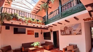 Amplia sala de estar con techo alto, balcón con plantas y un mural en la pared.