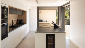 A modern kitchen with a central island, built-in appliances, and a view to an outdoor deck.