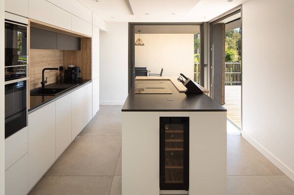 Una cocina moderna con una isla central, electrodomésticos integrados y vistas a una terraza exterior.