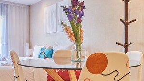 A modern dining area with a glass table, wooden chairs, and a vase of flowers. - Surf & Fun Beachfront Stay in Mirleft With Balcony (Mirleft)