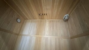 Teto de madeira com sistema de ventilação central e duas luminárias fixadas na parede.