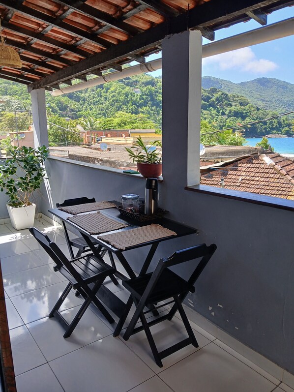 A balcony with a table and chairs, a potted plant, and a view of a mountainous landscape.