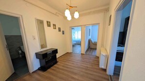 Un'ampia zona giorno con pavimento in legno, un mobile intrattenimento nero e un lampadario a soffitto.
