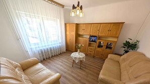 Un soggiorno con due divani in pelle, un tavolino rotondo con un vaso, pensili in legno e una TV.