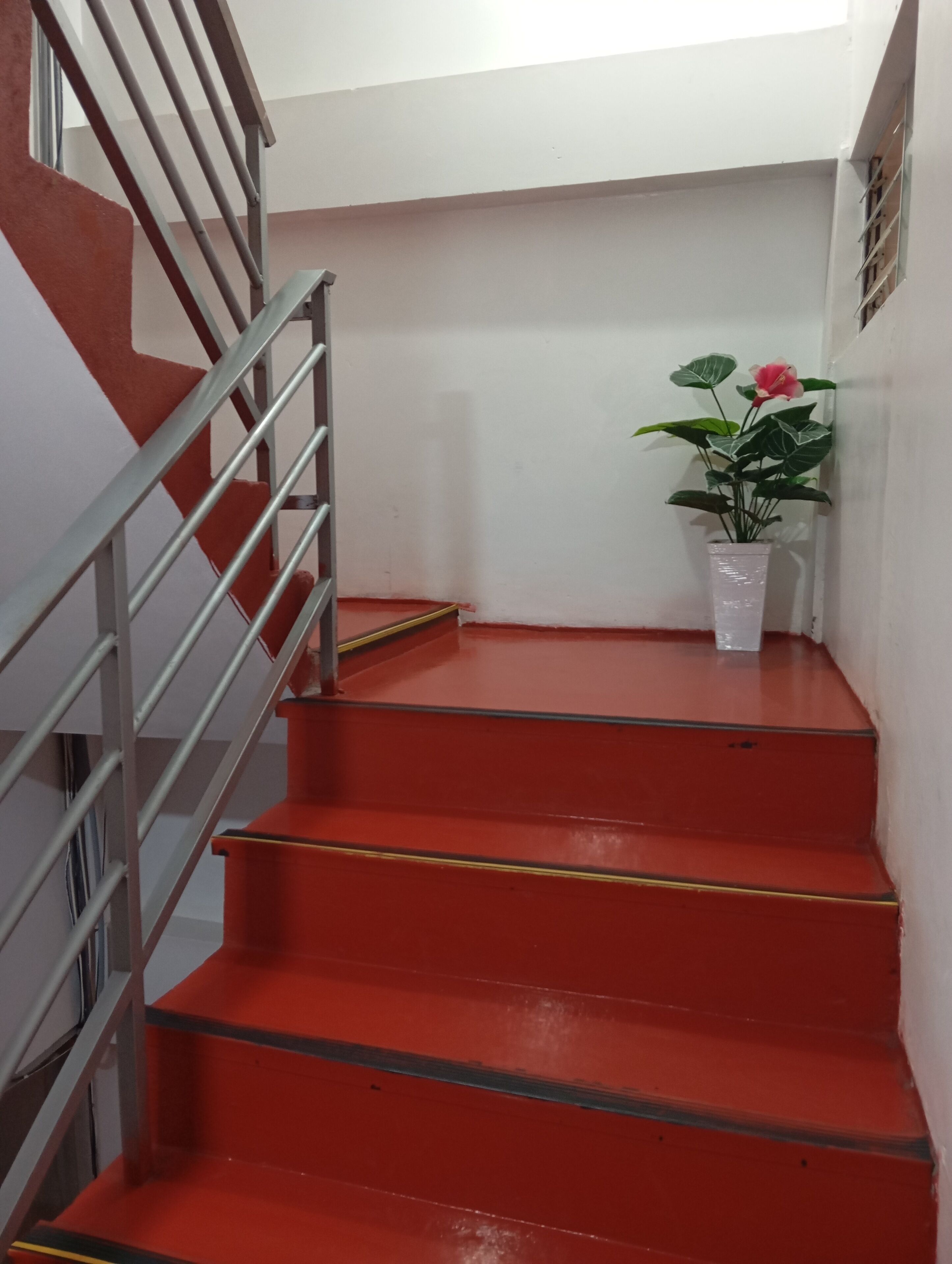 A staircase with red steps and a metal railing.