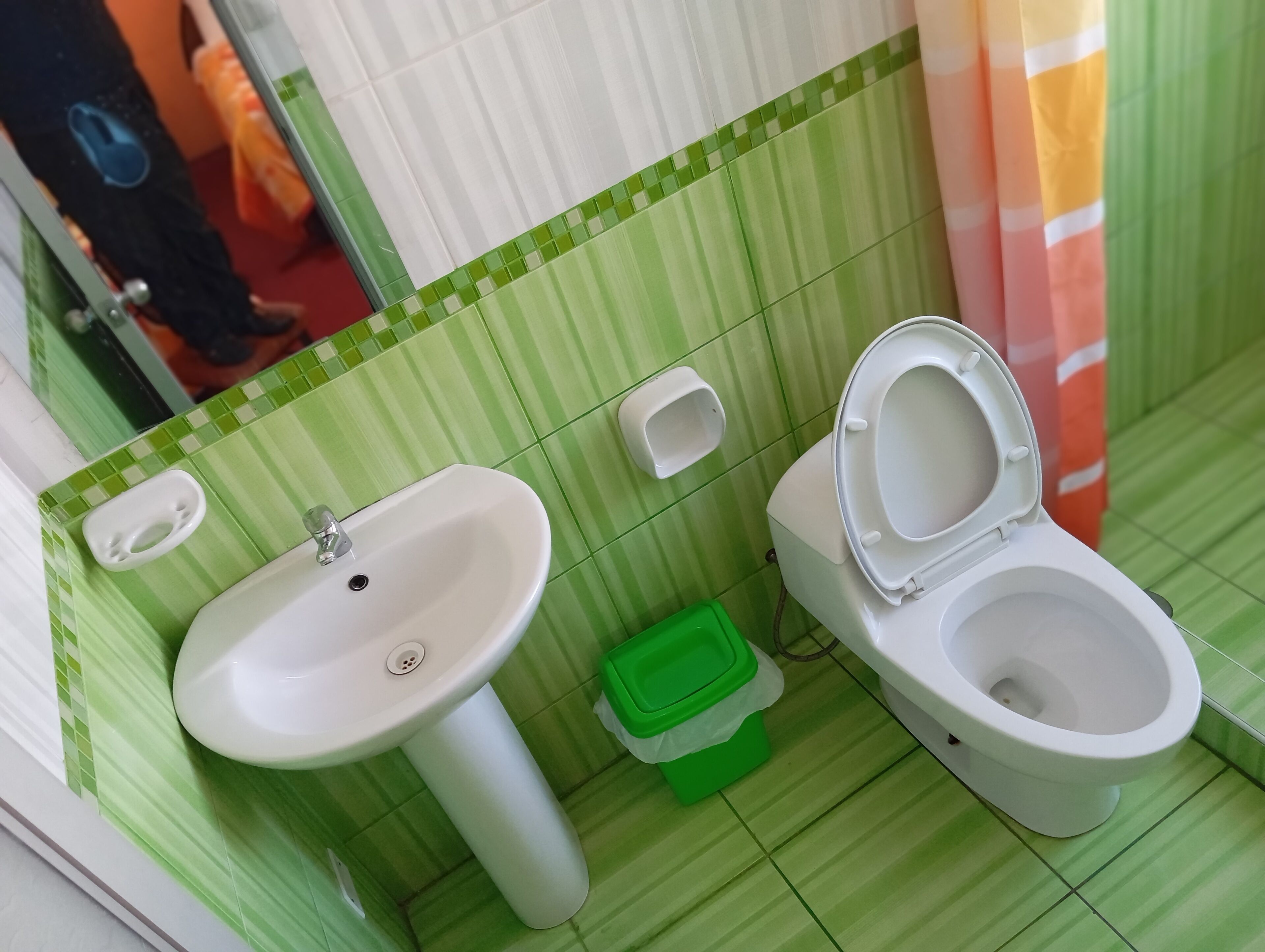 A bathroom with a sink, toilet, and green-striped tiles.