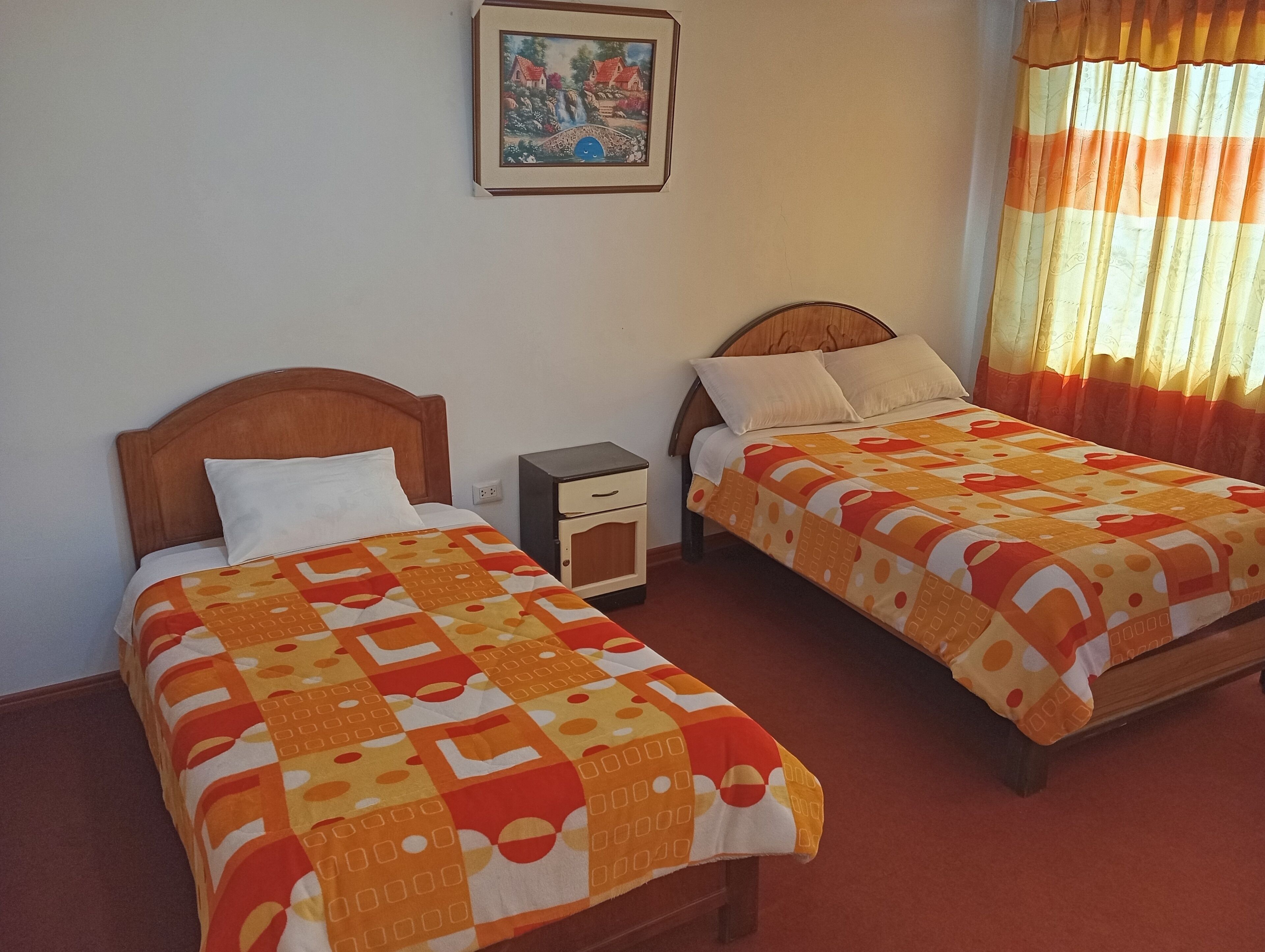 Two single beds with wooden headboards, a nightstand, and a framed picture on the wall.