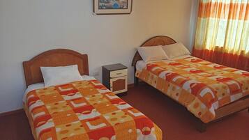 Two single beds with wooden headboards, a nightstand, and a framed picture on the wall.