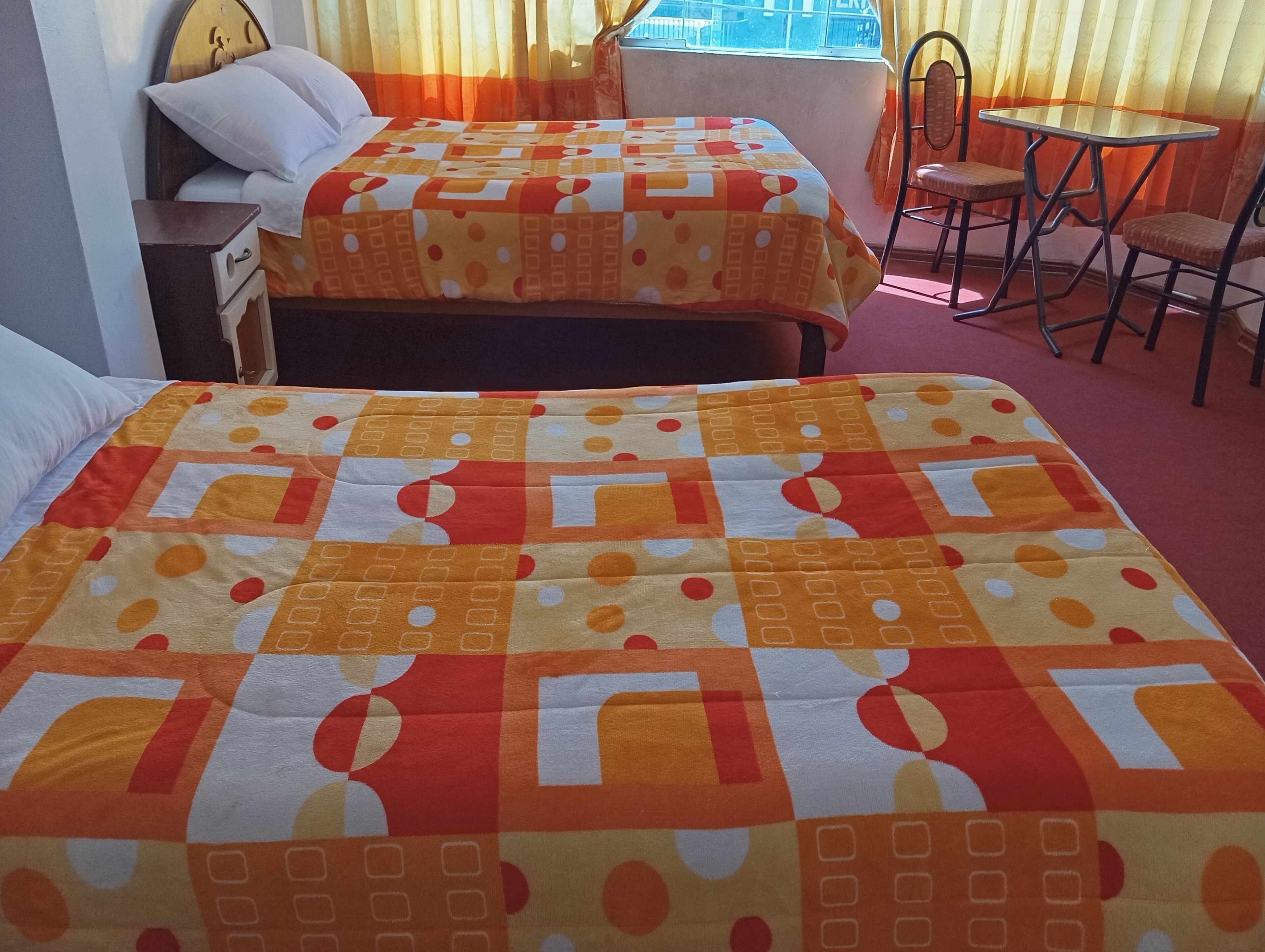 Une chambre d’hôtel avec deux lits, une petite table et une chaise.