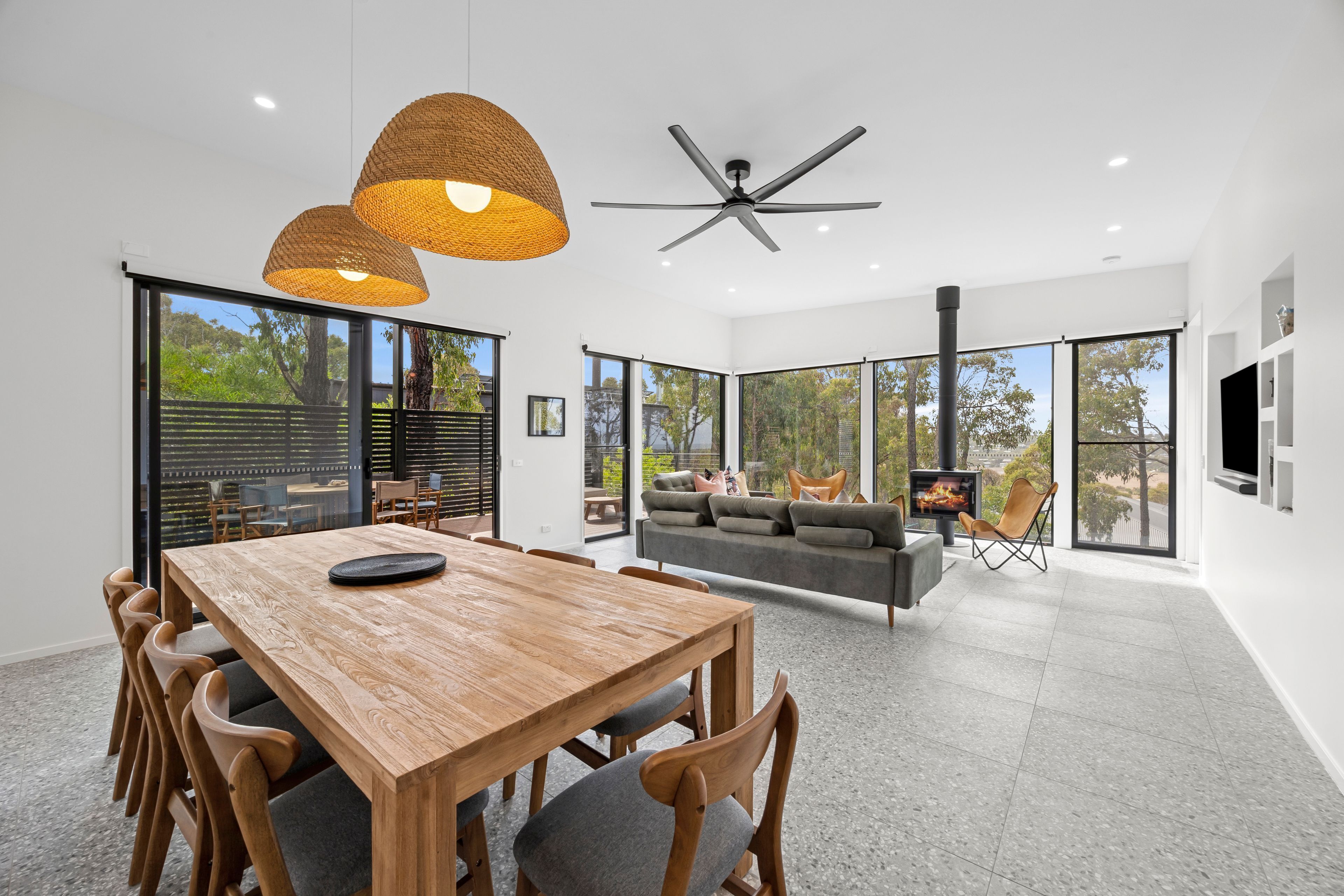 Ein modernes Interieur mit einem Holztisch, einer Couch und einem Deckenventilator.