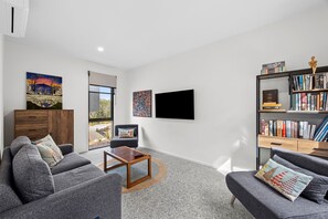 A modern living room with grey sofas, a coffee table, a bookshelf, and artwork on the walls. - Belmare - A Perfect Escape Surrounded by Nature (Fairhaven)