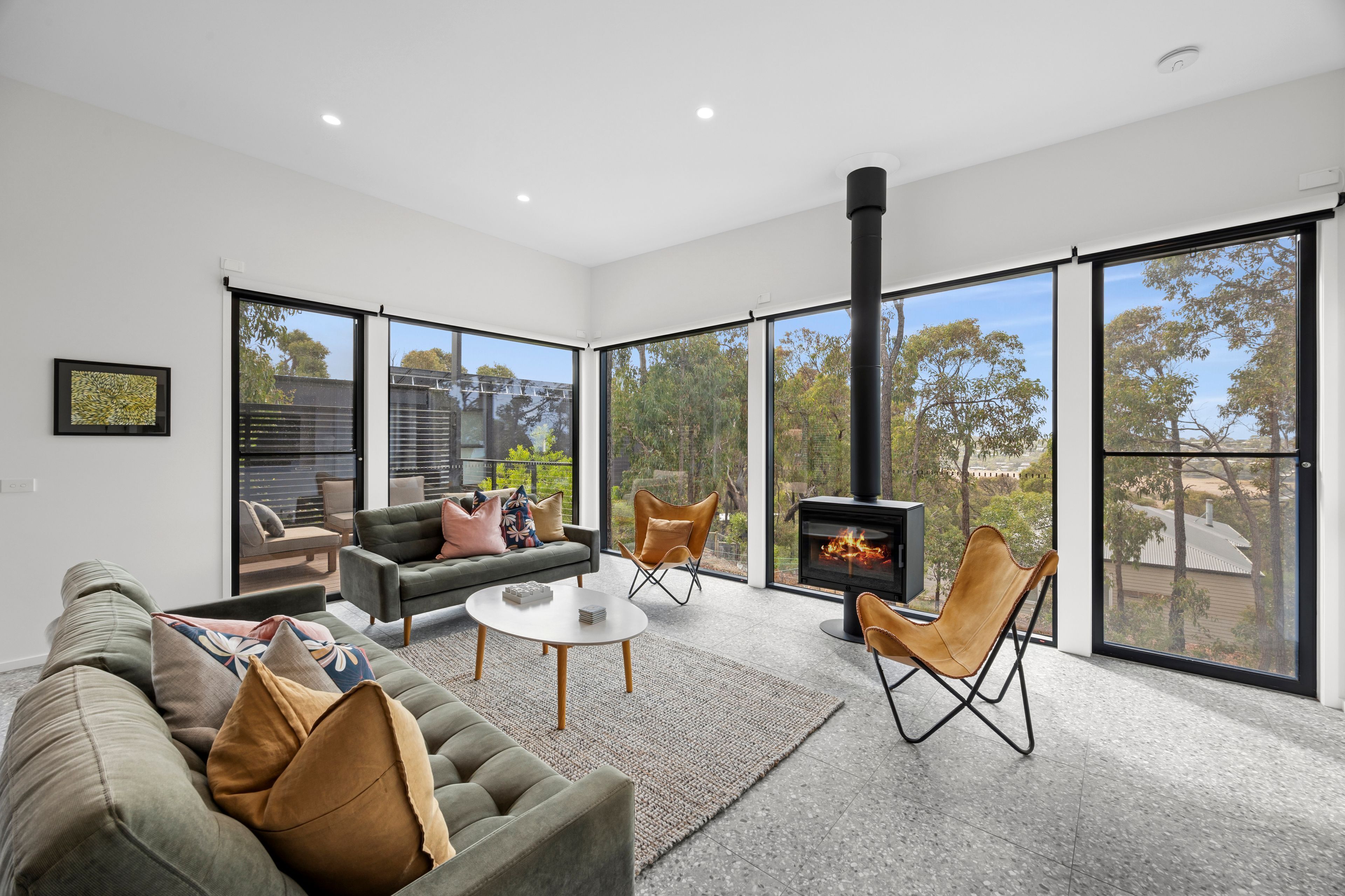 A modern living room with a fireplace, large windows, and a view of the outdoors.