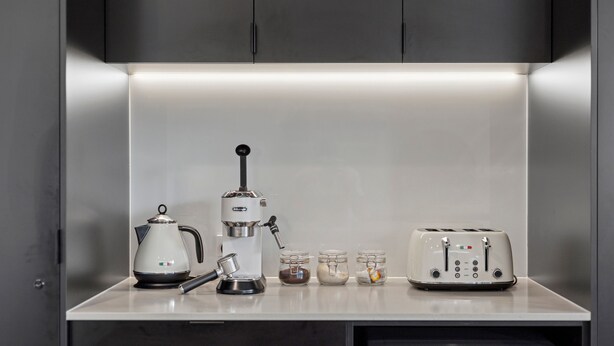 A kitchen counter with a coffee maker, a kettle, a toaster, and three glass jars with lids. - Belmare - A Perfect Escape Surrounded by Nature (Fairhaven)