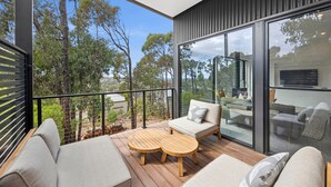 A modern balcony with a wooden table and two sofas, overlooking a scenic landscape. - Belmare - A Perfect Escape Surrounded by Nature (Fairhaven)