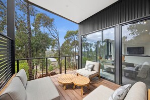 A modern balcony with a wooden table and two sofas, overlooking a scenic landscape. - Belmare - A Perfect Escape Surrounded by Nature (Fairhaven)