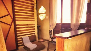 A cozy room with a wooden slatted wall, a cushioned bench, a bar area, and a window with curtains. - Buena Vista Bio Chalet (High Paradise of Goiás)