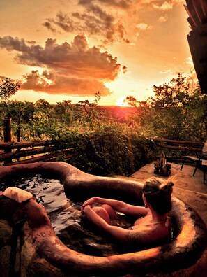 A person relaxing in a hot tub with a sunset view.