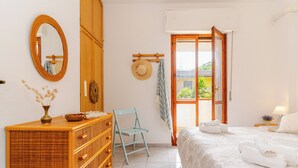 A bedroom with a bed, a dresser, a chair, a mirror, and a view of the outside. - Villa see view - 5min walk to the beach (Scaro-reggio-Scornavacca-vardano)