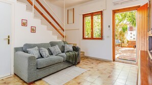 A living room with a grey sofa, wooden staircase, and a large window with a view of the outdoors. - Villa see view - 5min walk to the beach (Scaro-reggio-Scornavacca-vardano)