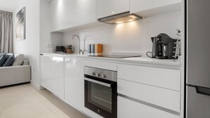 A modern kitchen with white cabinetry, a built-in oven, a coffee machine, and a sink. - Top Floor Seaview Apartment (Estepona)
