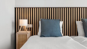 A hotel room with a wooden slat headboard, a bedside table with a lamp, and a bed with white bedding and blue pillows. - Top Floor Seaview Apartment (Estepona)