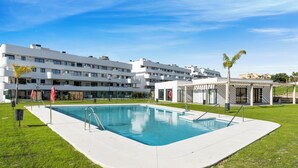 A modern hotel with a swimming pool, multiple balconies, and a well-maintained lawn. - Top Floor Seaview Apartment (Estepona)