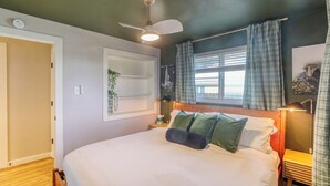 A bedroom with a bed, a ceiling fan, a bedside table with a lamp, a window with curtains, and a wall-mounted shelf with a plant. - New Remodel! +5 bedroom+Game Room+Sauna+Theater (Denver)