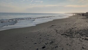 Une plage parsemée d'empreintes et un ciel dégagé.