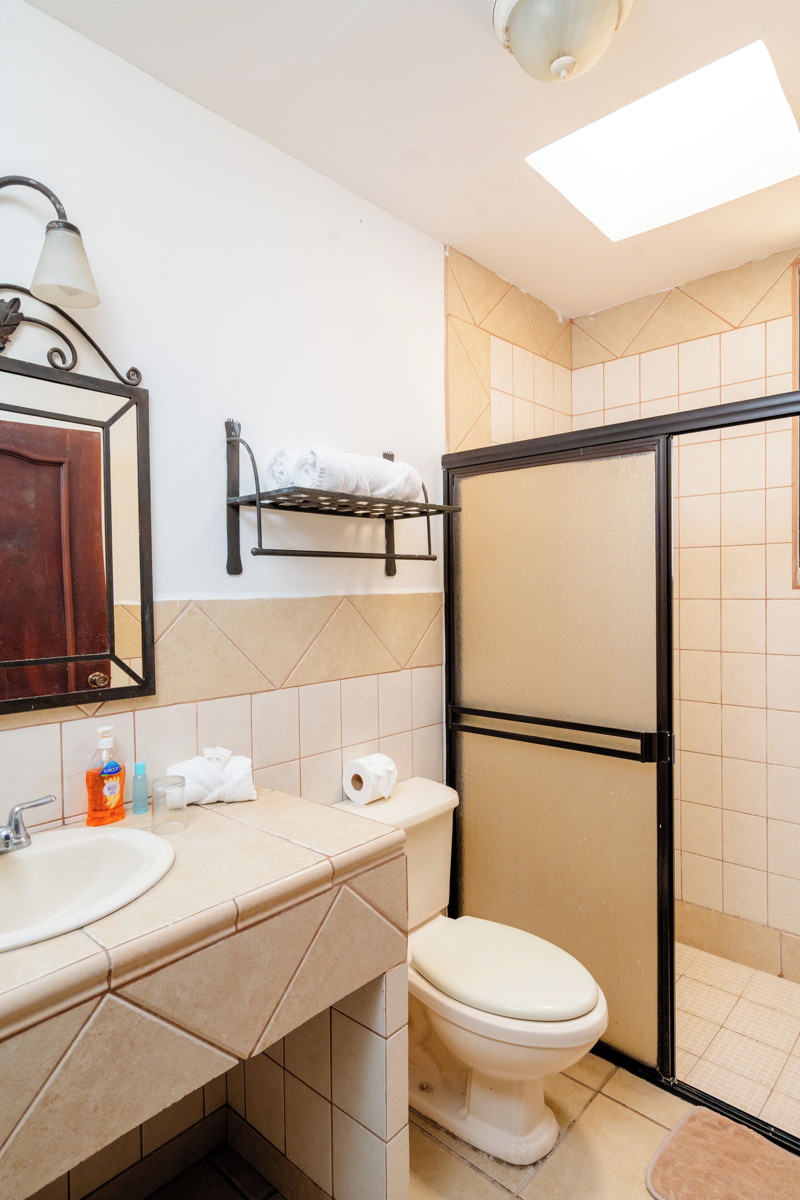 A bathroom with a toilet, sink, and a shower enclosure.