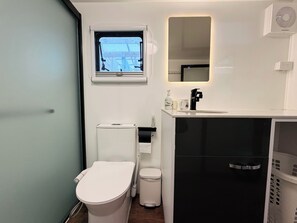 A modern bathroom with a toilet, bidet, sink, and a small window. - Top Hill House (Maungatapere)