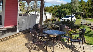 Une terrasse avec une table et des chaises, un palmier et une clôture blanche.